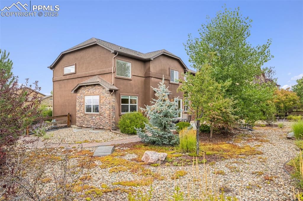 Image 38 of 50: Rear view of property featuring stone siding and stucco siding