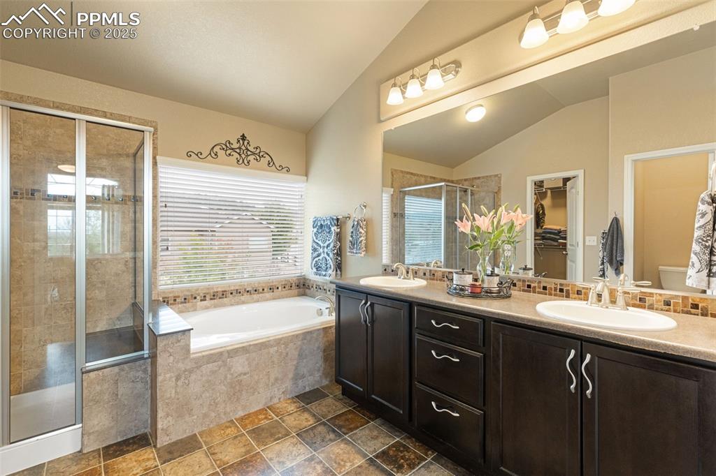 Image 4 of 50: Bathroom with vaulted ceiling, a stall shower, a garden tub, double vanity,