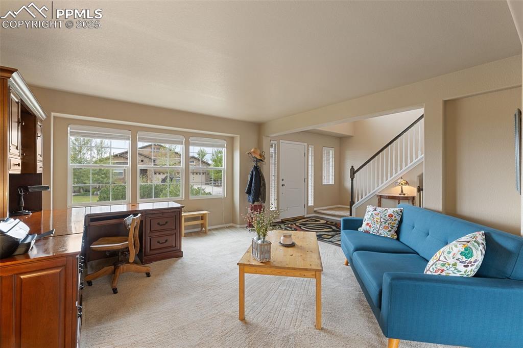 Image 7 of 50: Carpeted living room with stairway and an office area