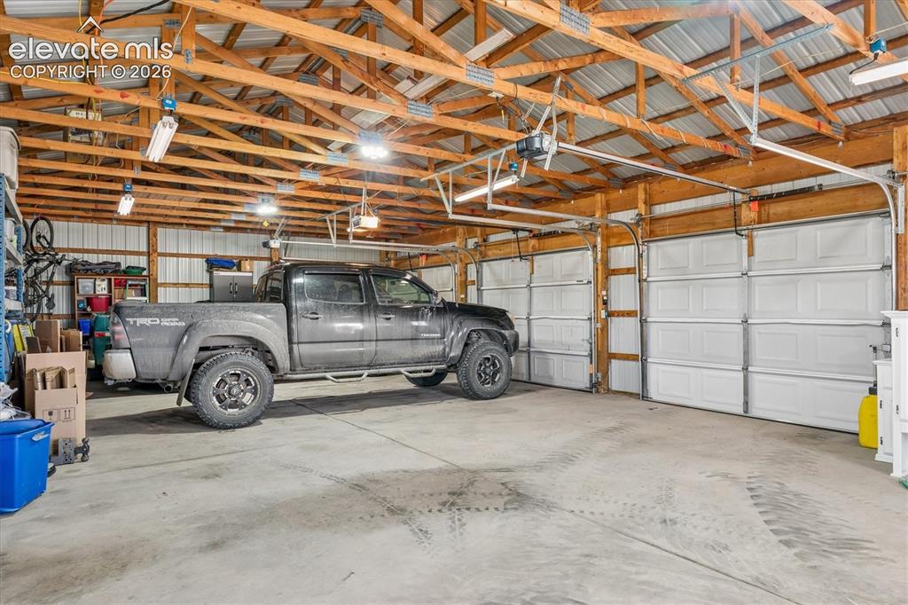 Image 24 of 34: Spacious garage featuring a concrete floor, exposed wood beam ceiling, mult