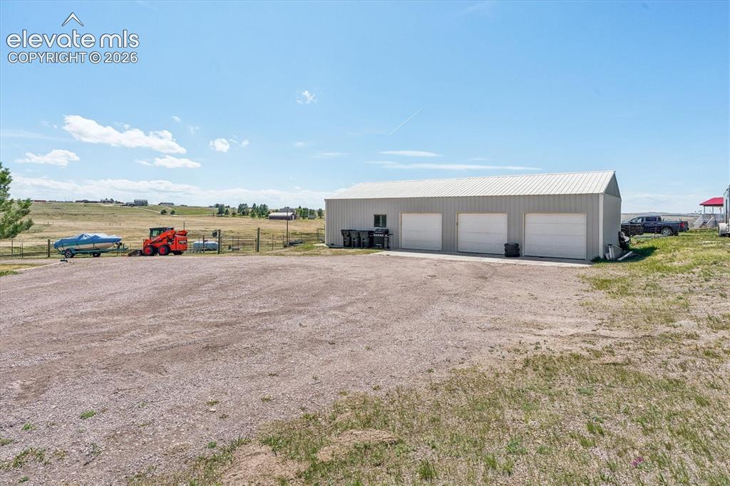 Image 26 of 34: Metal-sided outbuilding featuring three garage doors, a sloped roofline, an
