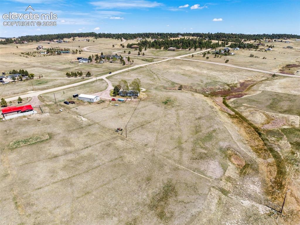 Image 30 of 34: Expansive rural property featuring a main residence, a red-roofed barn, an
