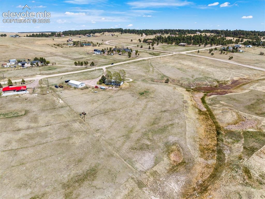 Image 31 of 34: Expansive land parcel featuring a natural watercourse and mature trees