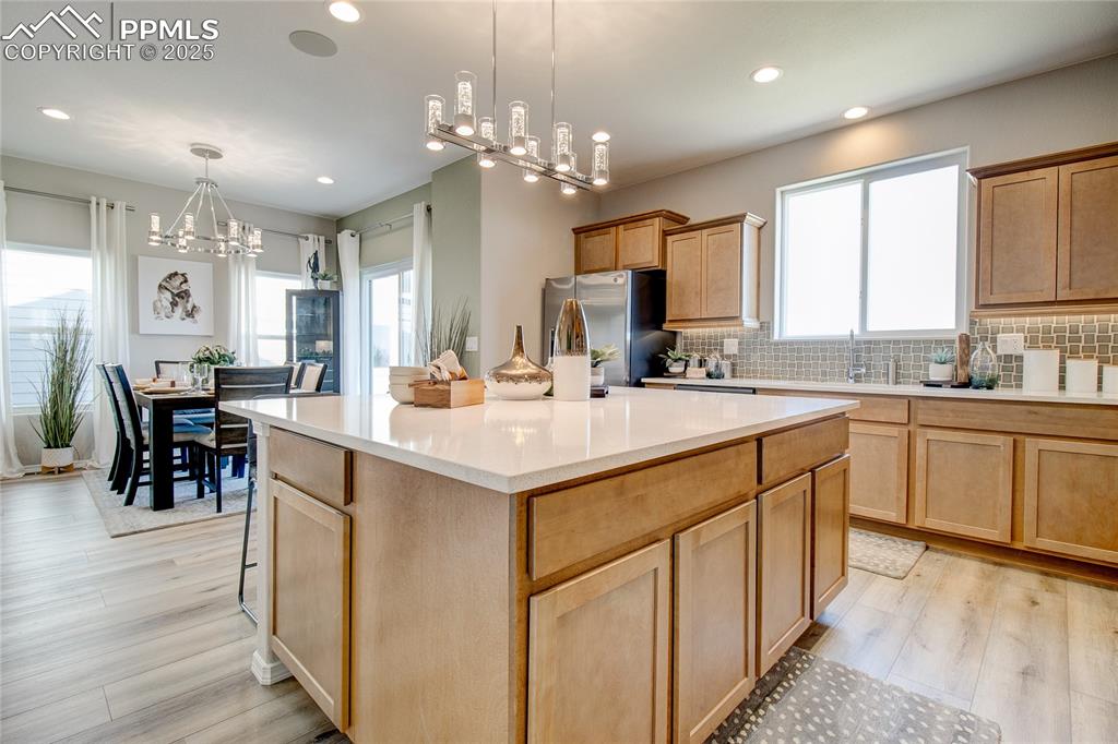 Image 10 of 30: Kitchen featuring decorative backsplash, a chandelier, hanging light fixtur