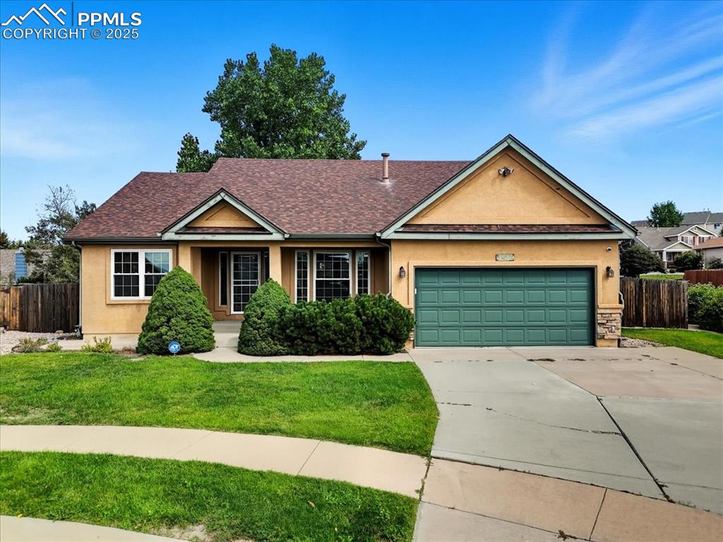 Caption: Ranch-style house featuring stucco siding, a shingled roof, concrete driveway, and an attached garag
