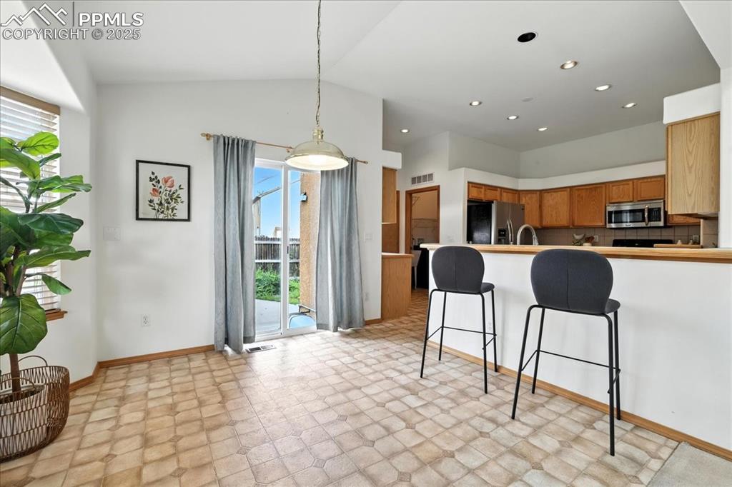 Image 10 of 50: Kitchen with light flooring, vaulted ceiling, stainless steel appliances, a