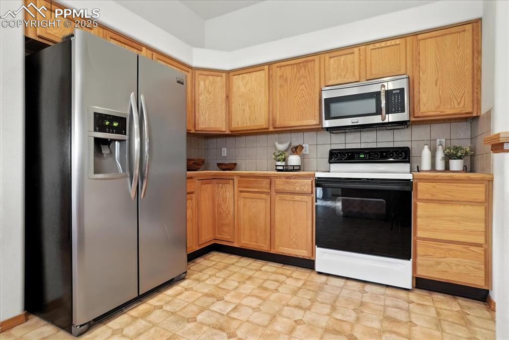 Image 14 of 50: Kitchen with light floors, stainless steel appliances, and decorative backs
