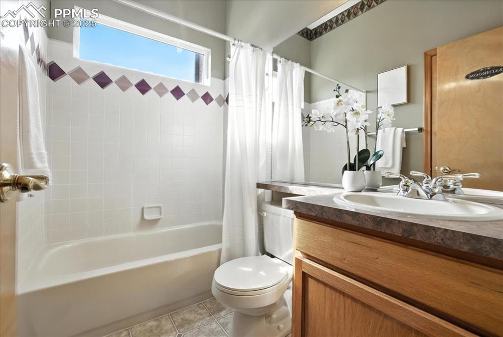 Image 23 of 50: Bathroom featuring vanity, shower / bath combo with shower curtain, and til
