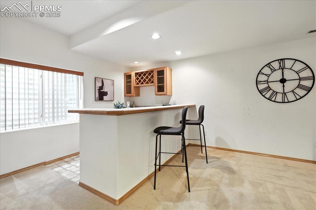 Image 26 of 50: Indoor bar featuring light carpet and recessed lighting
