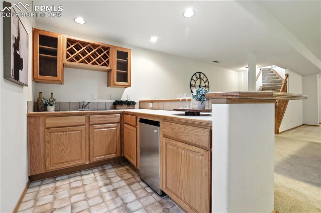 Image 27 of 50: Kitchen with light flooring, a peninsula, glass insert cabinets, recessed l