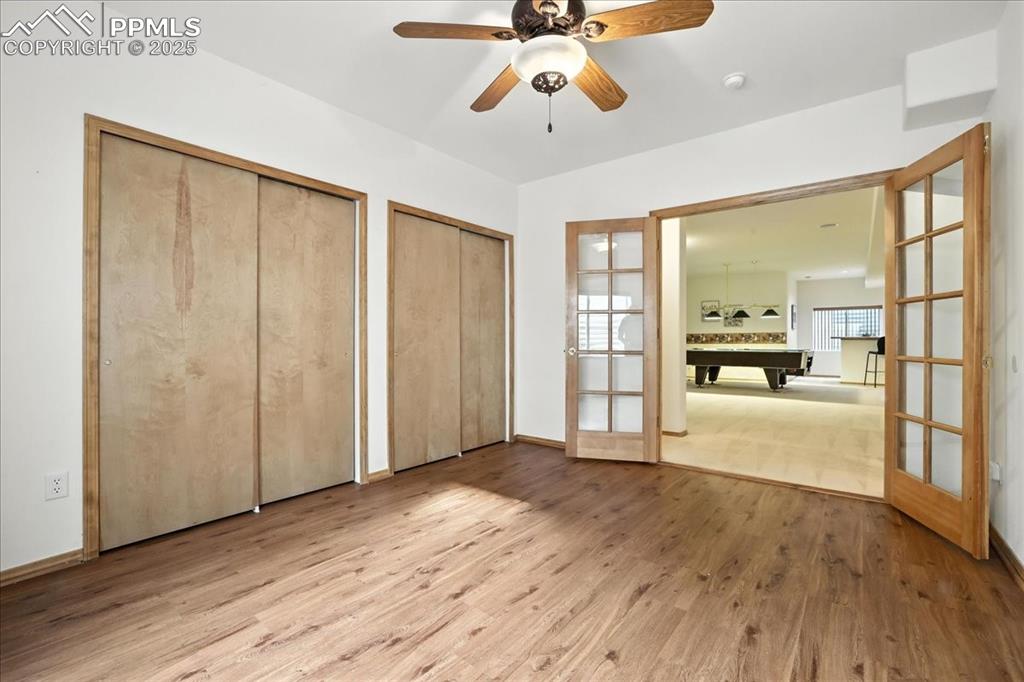 Image 32 of 50: Unfurnished bedroom featuring two closets, billiards, wood finished floors,