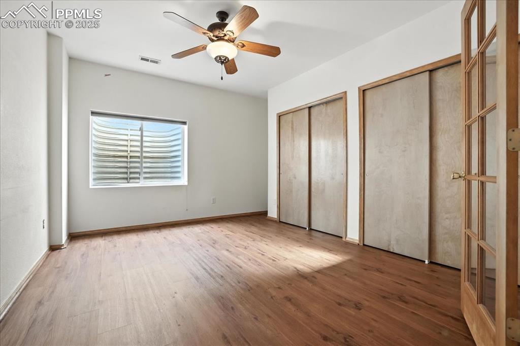 Image 33 of 50: Unfurnished bedroom with two closets, wood finished floors, and a ceiling f