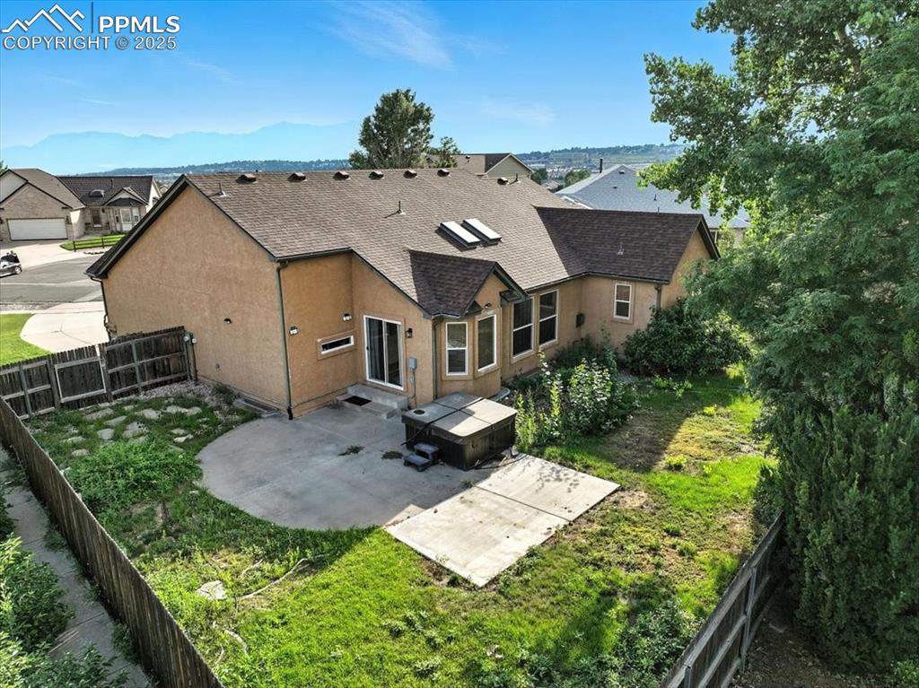 Image 39 of 50: Back of house with a patio area, a shingled roof, stucco siding, and a fenc