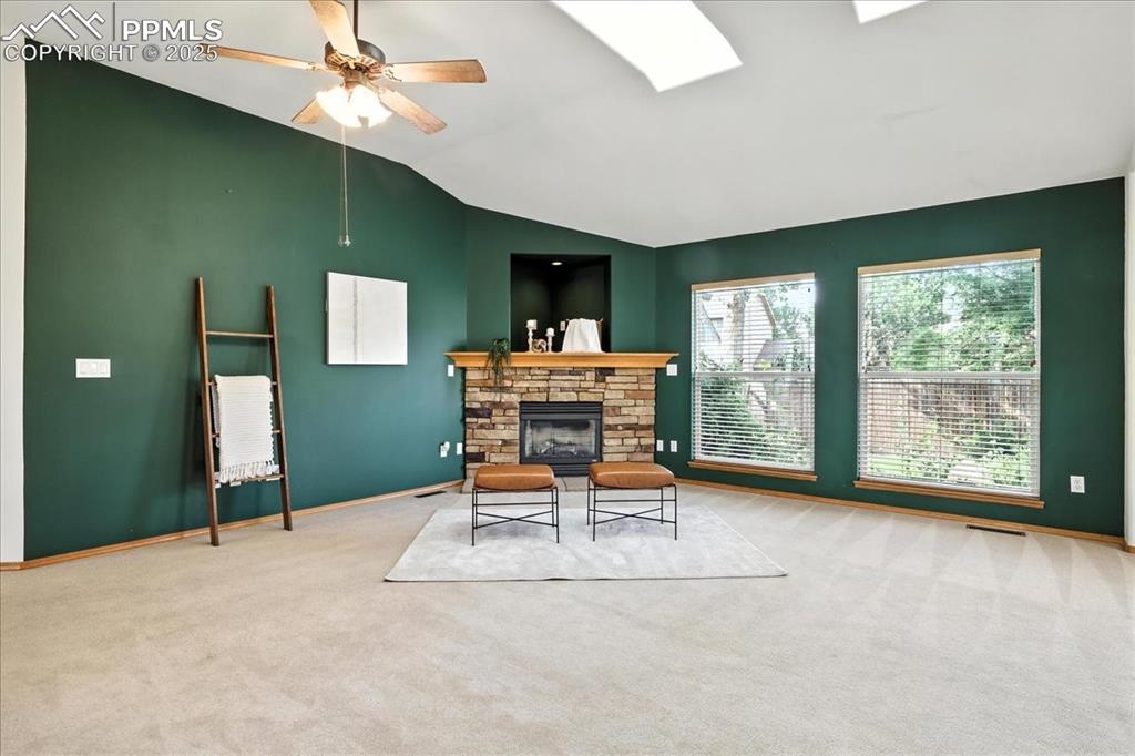 Image 8 of 50: Carpeted living room featuring lofted ceiling, ceiling fan, a skylight, and