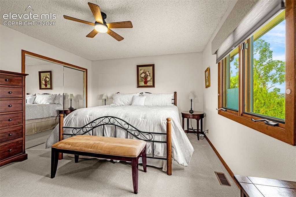Image 12 of 42: Primary bedroom with ceiling fan, large window and ensuite bathroom