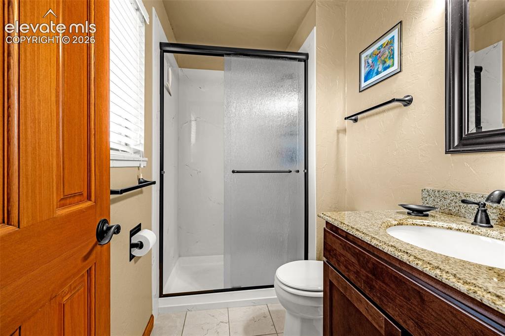 Image 14 of 42: Primary bathroom with walk-in shower, granite counters and tile flooring