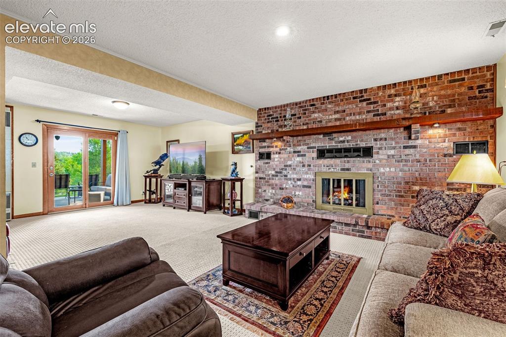 Image 20 of 42: Large family room downstairs with second gas fireplace