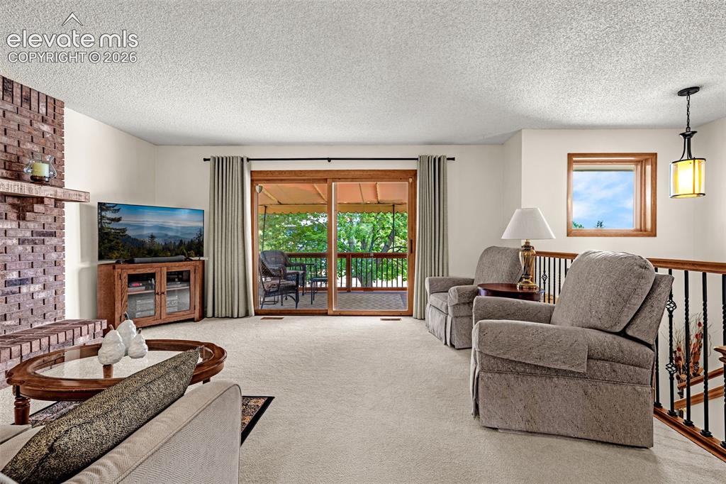Image 4 of 42: Living room with walk-out to deck and cozy gas fireplace