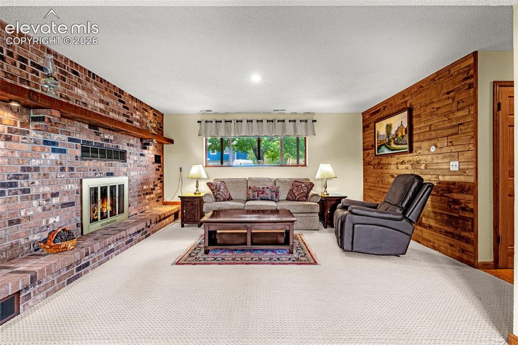 Image 6 of 42: Downstairs family room with second gas fireplace and wood accent wall