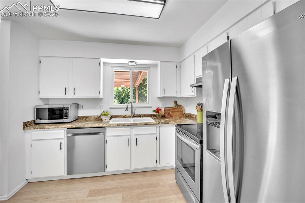 Image 13 of 34: Kitchen featuring appliances with stainless steel finishes, light wood fini