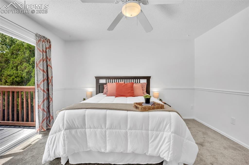 Image 17 of 34: Carpeted bedroom with a textured ceiling and ceiling fan