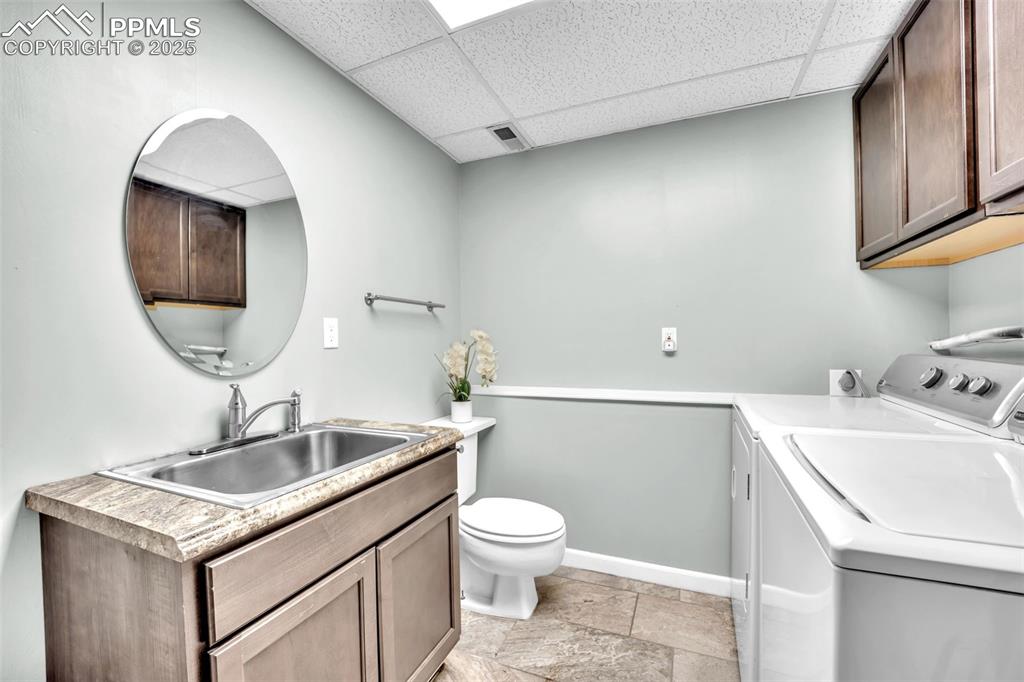 Image 23 of 34: Bathroom with a drop ceiling, vanity, and washer and dryer