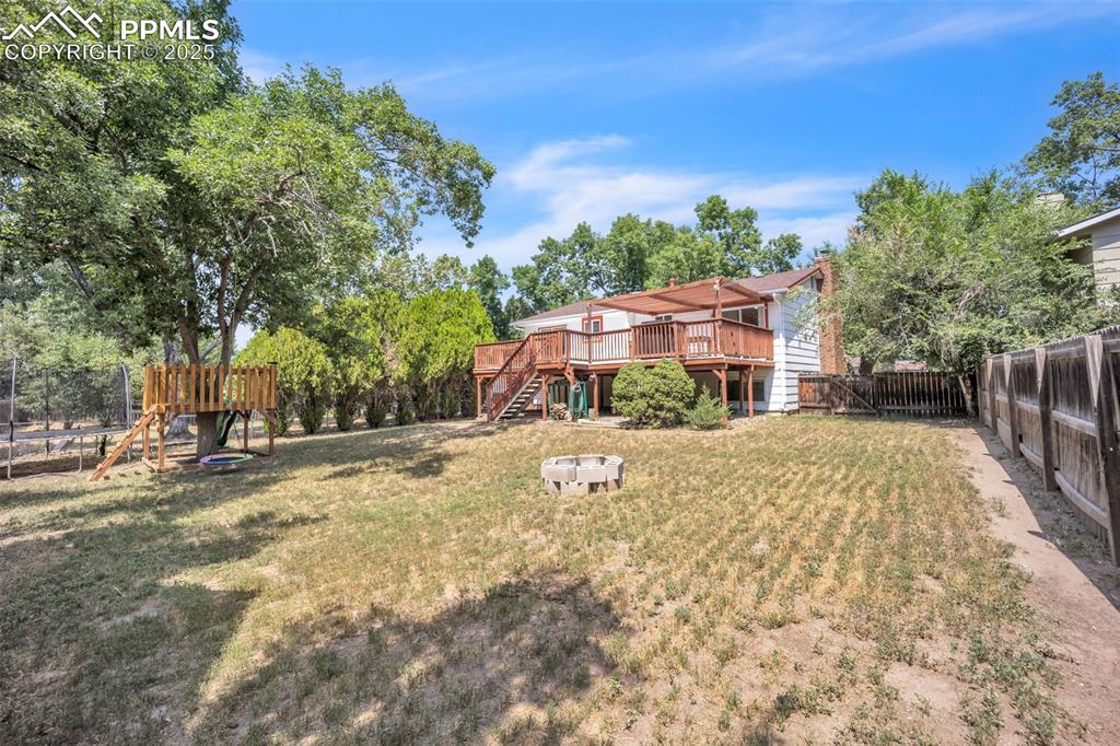 Image 32 of 34: Large back yard with firepit and tree house