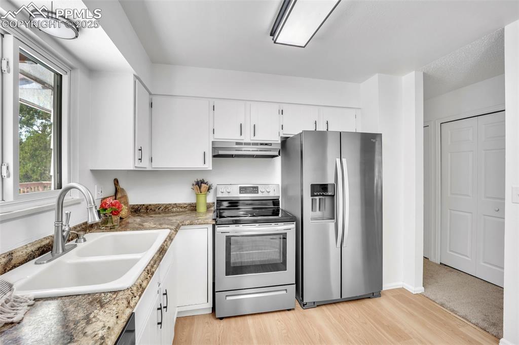 Image 5 of 34: Kitchen featuring appliances with stainless steel finishes, white cabinets,