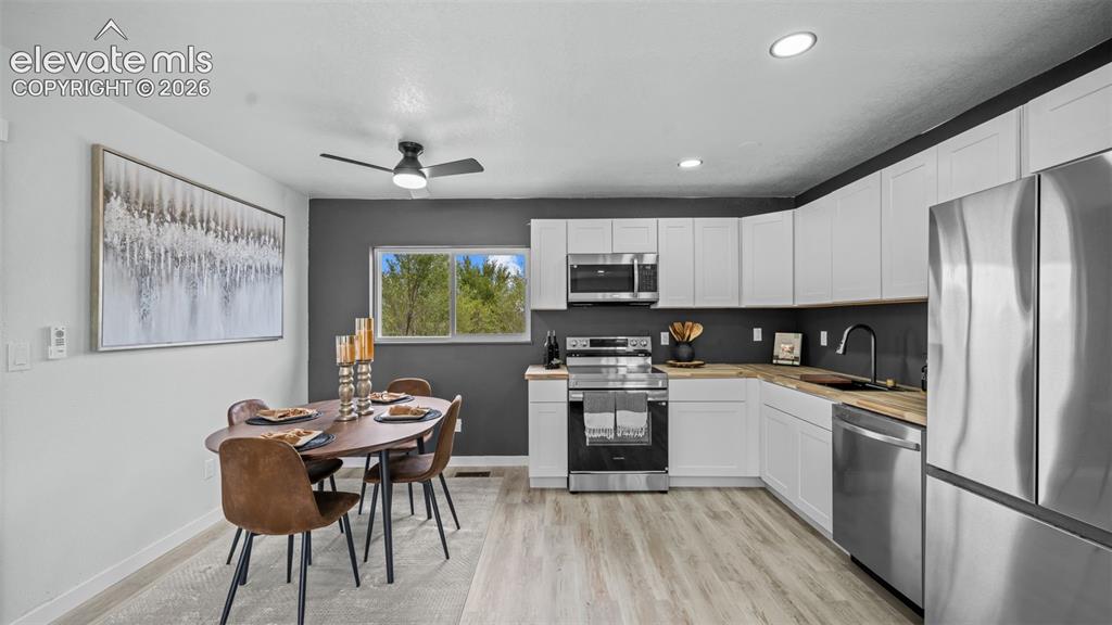 Image 12 of 31: White cabinetry, stainless steel appliances, wood-finish countertops, reces