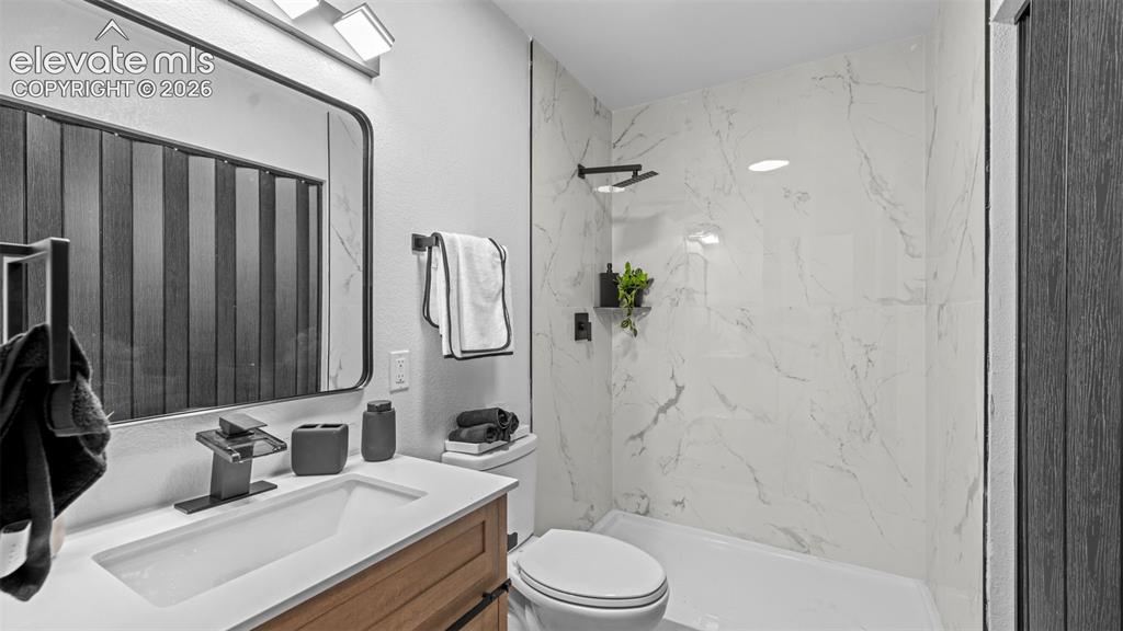 Image 15 of 31: White vanity with an integrated rectangular sink, wood-finish cabinetry, an