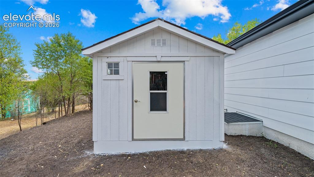 Image 22 of 31: Detached storage shed with white board-and-batten siding, a pitched roof, a