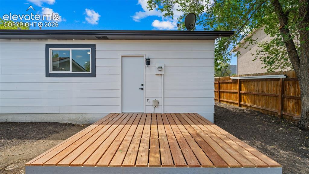 Image 23 of 31: New wood decking, white horizontal siding, dark trim window, exterior door,