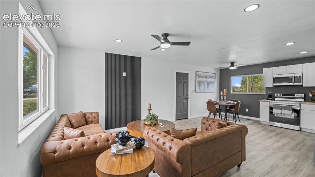 Image 5 of 31: Open-concept living space with wood-finish flooring, recessed lighting, and