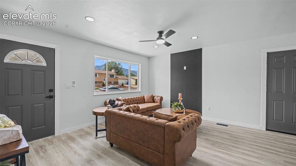 Image 6 of 31: Light wood-finish flooring, recessed lighting, and a modern ceiling fan