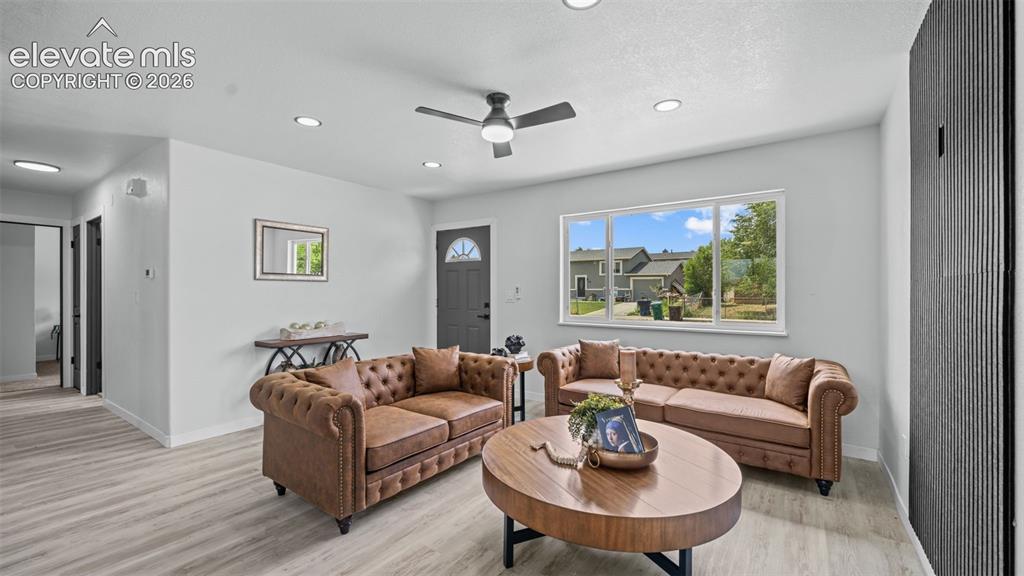 Image 7 of 31: Light wood-finish flooring, recessed lighting, ceiling fan, dark gray entry