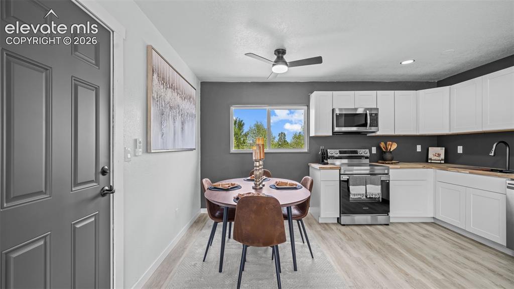 Image 8 of 31: Updated kitchen with white cabinetry and wood-finish countertops, stainless