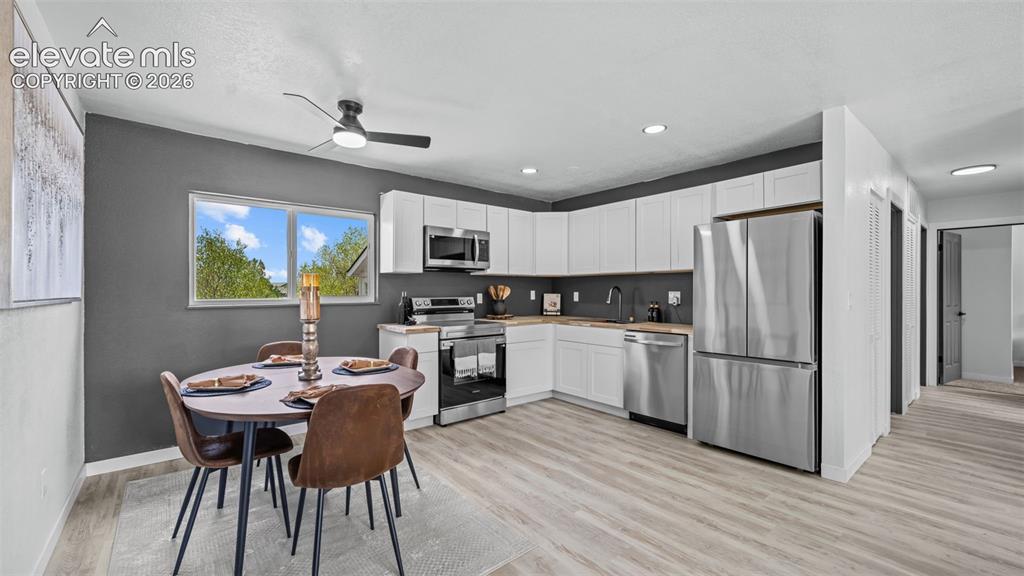 Image 9 of 31: Kitchen featuring white cabinetry, stainless steel appliances, wood-finish 