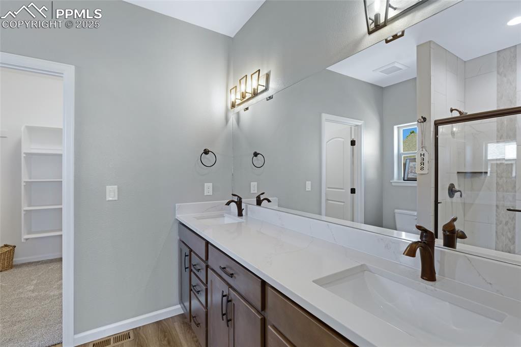 Image 16 of 41: Full bathroom featuring a shower stall, double vanity, and light wood-style