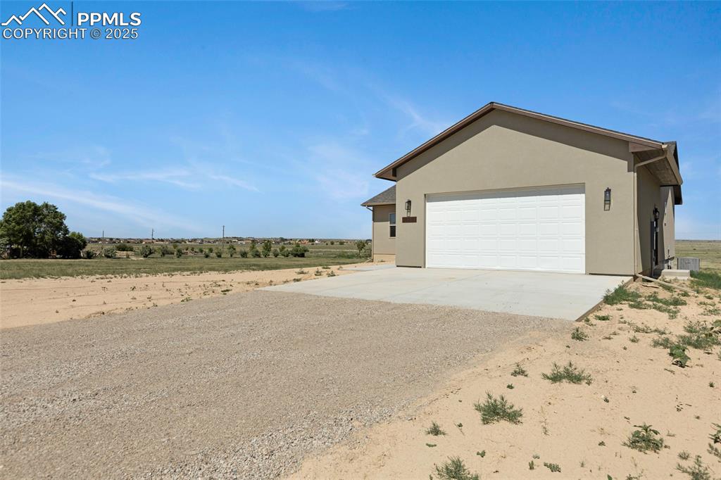 Image 2 of 41: View of side of property featuring driveway and stucco siding