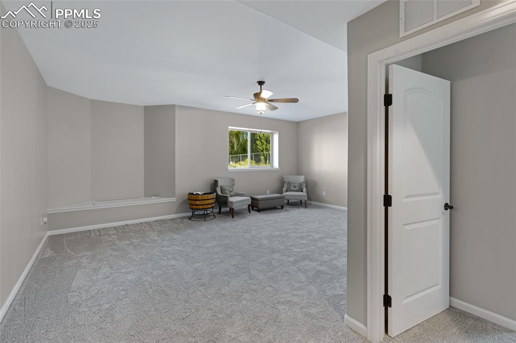 Image 22 of 41: Living area with light carpet and a ceiling fan
