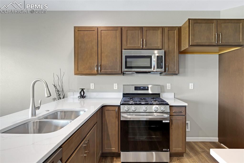 Image 9 of 41: Kitchen with appliances with stainless steel finishes, dark wood-style floo