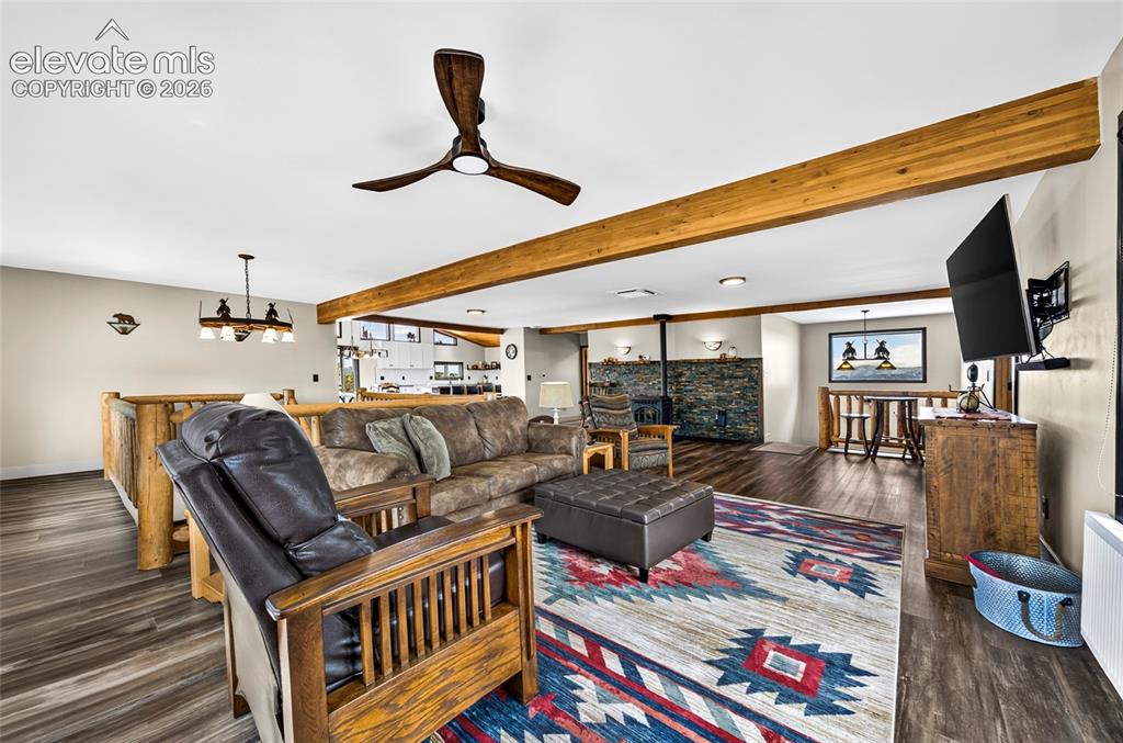 Image 12 of 45: Open-concept living area featuring wood-finish flooring, exposed wood beams