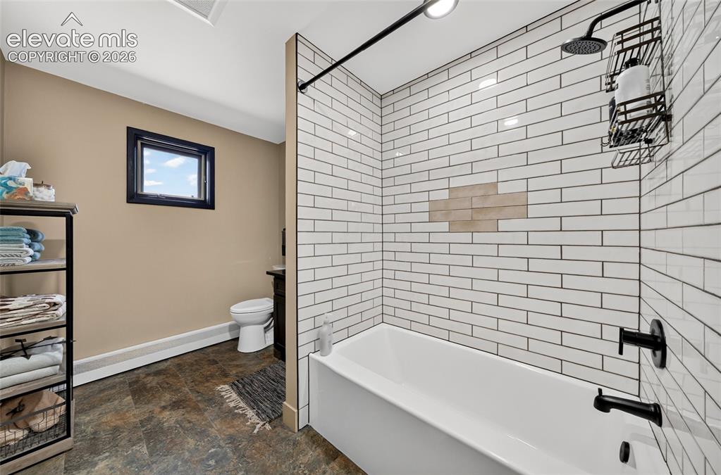 Image 23 of 45: Bathtub with subway tile surround, matte black shower fixtures, and a rain