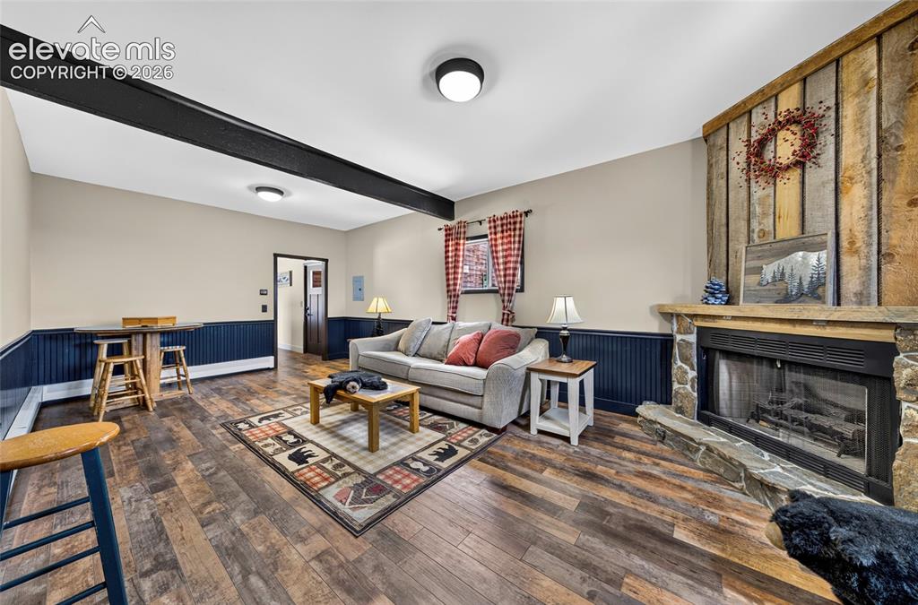 Image 28 of 45: Wood-finish flooring, stone fireplace with a wood mantle, wood paneling, wo