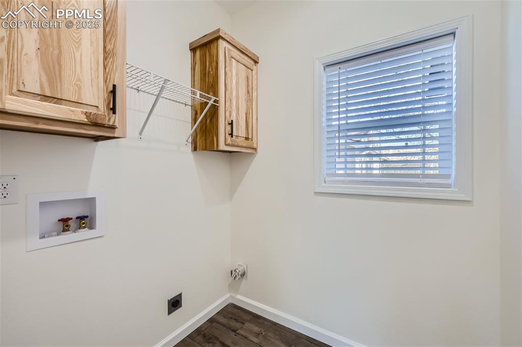 Image 15 of 16: Laundry area with dark wood finished floors, cabinet space, hookup for a wa