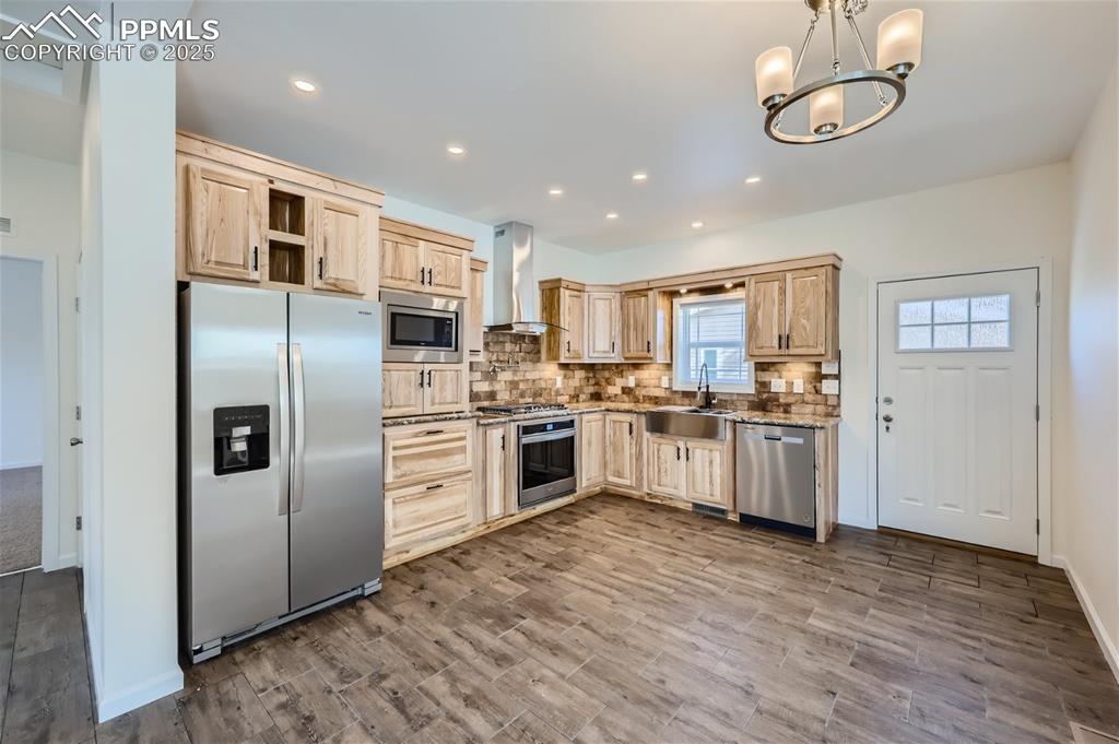 Image 7 of 16: Kitchen with appliances with stainless steel finishes, backsplash, light br