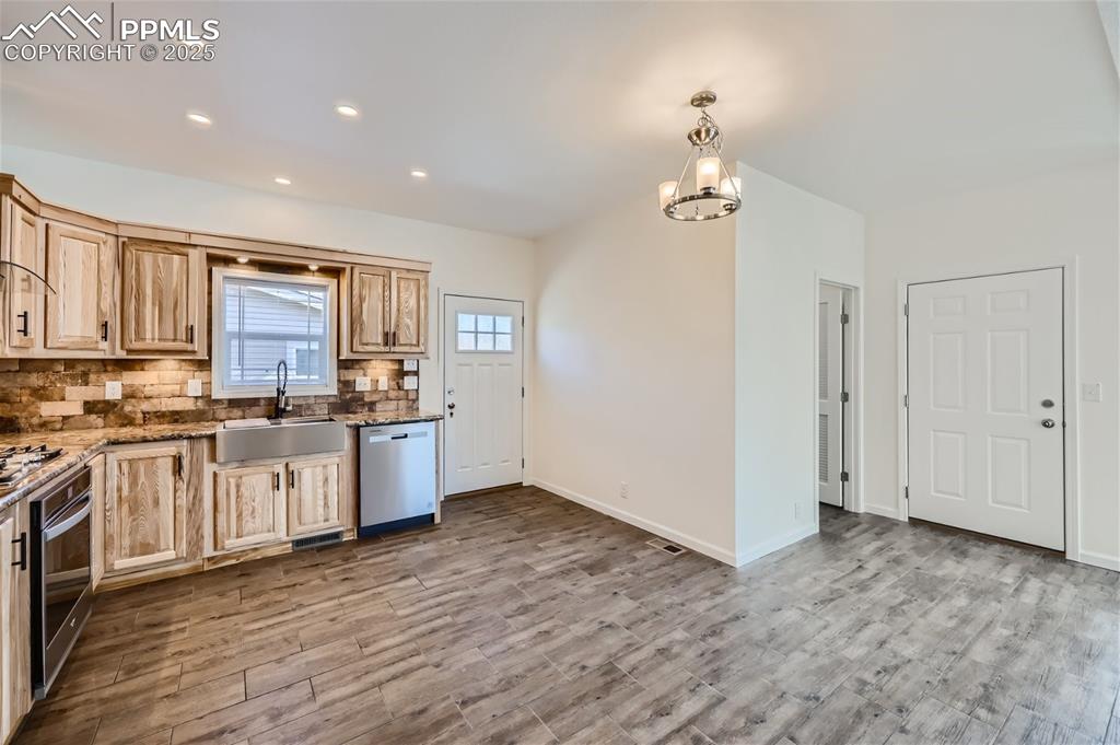 Image 8 of 16: Kitchen featuring backsplash, dark stone countertops, hanging light fixture
