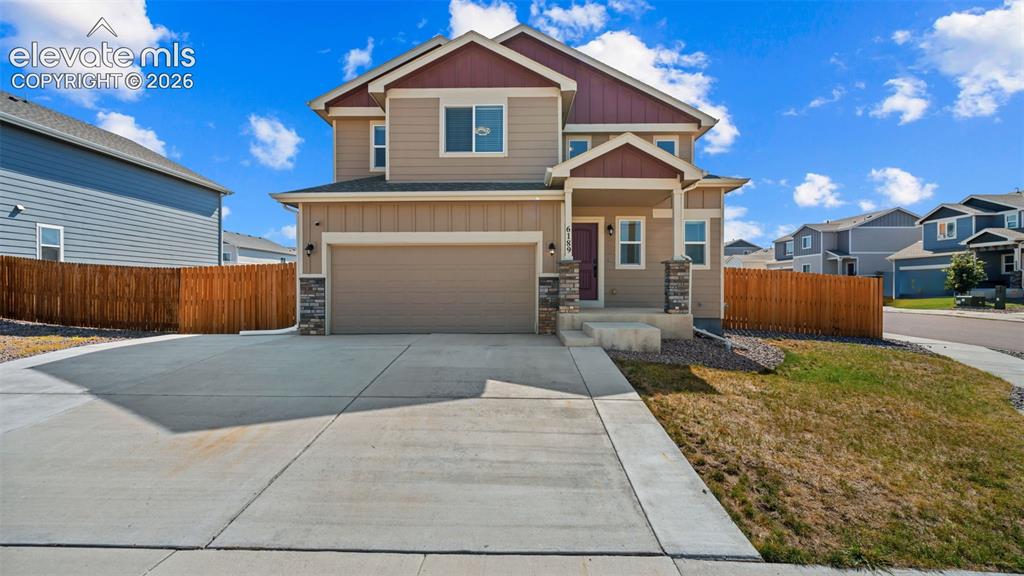 Caption: Two-story residence featuring a two-car garage, concrete driveway, stone column accents, and a cover
