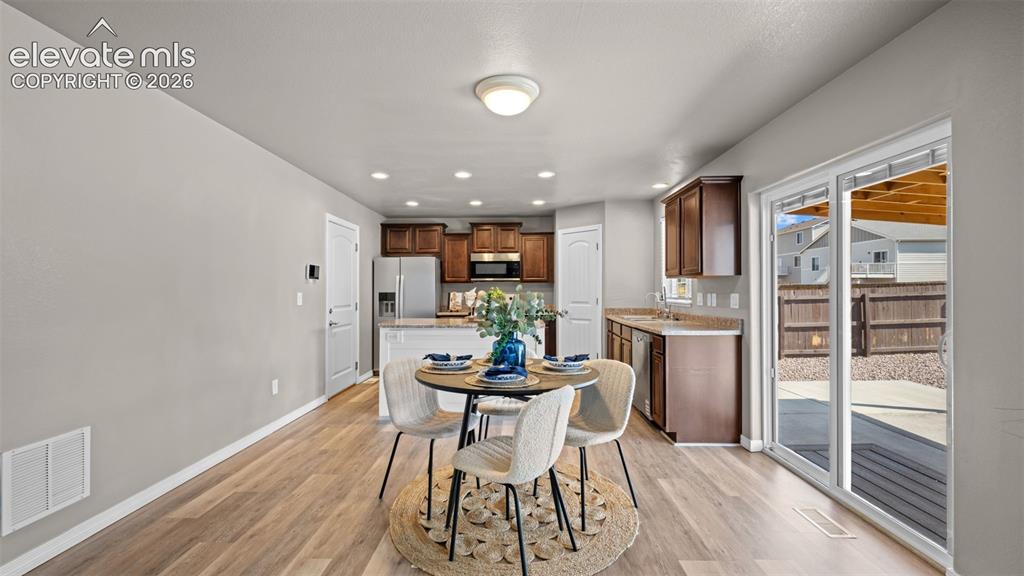 Image 12 of 43: Open-concept dining area with wood-finish flooring, recessed lighting, and 