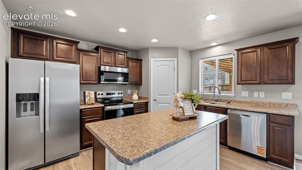 Image 14 of 43: Kitchen featuring an island with a light-toned countertop, wood-finish floo